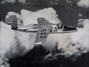 A black & white image showing the Second Saab 105 prototype mid-flight. The aircraft is mostly unpainted, while carrying civilian markings.